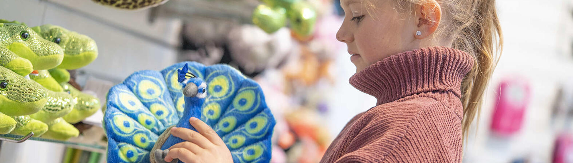 A girl looking at one of the plush toys at Zoo Shop