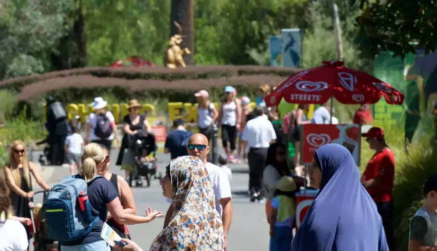 A view of the crowded Main Drive at Melbourne Zoo, with a red Streets ice cream cart in the mid-ground and the gold Elephant statue in the background.